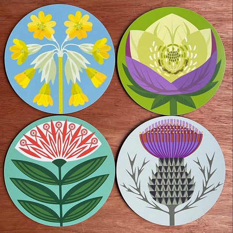 Four circular table mats wotwh flower designs hellebore thisstle dahlia cowslip