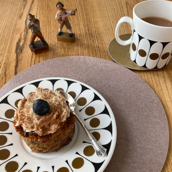Coffe and cake with wooden figures and rose colour table mat with flax colour coaster designed by Jenny Duff and made on melamine in the UK